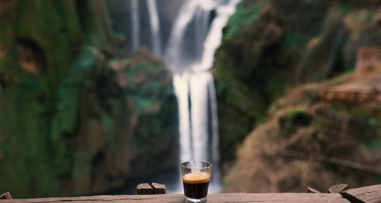 Tasse Espresso mit einem unscharfen Wasserfall im Hintergrund.