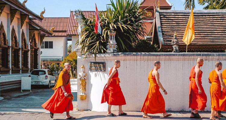 Monniken die voorbij een traditioneel gebouw lopen.