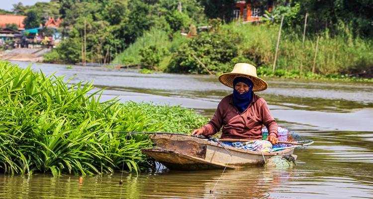 Een persoon die vist vanuit een kleine boot in een rivier.