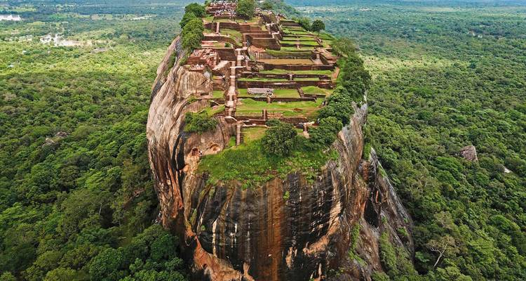 Drone view of Sigiriya rock fortress rising above dense Sri Lankan jungle.