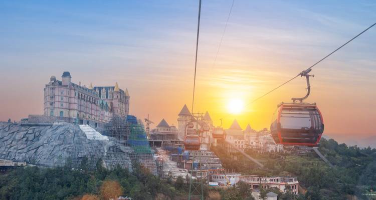 Cable car over a valley with sunset backdrop.