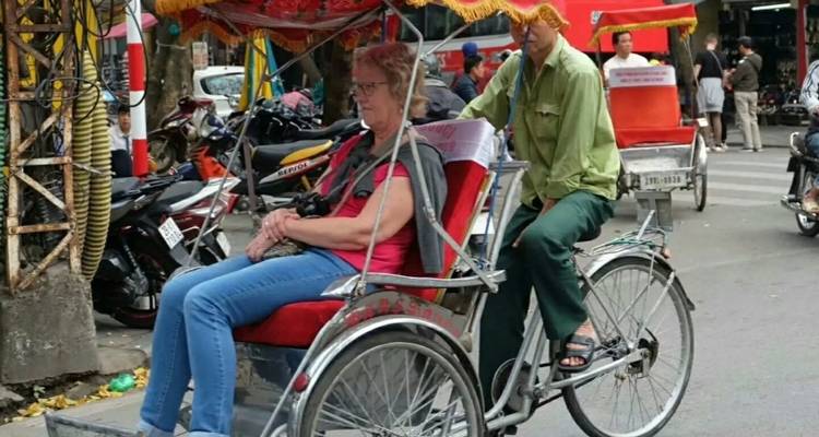 Persoon die een fietstaxi bestuurt met een passagier op straat.