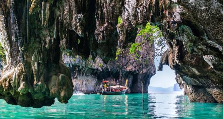 Boot die vaart door rotsformaties in helder turquoise water.
