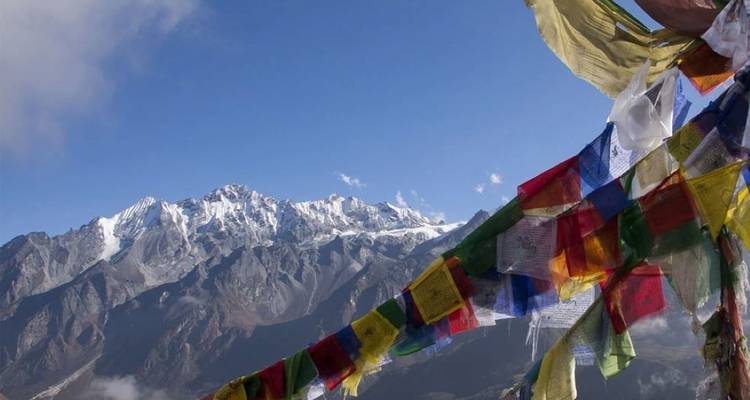 Colorful prayer flags with a mountain backdrop.