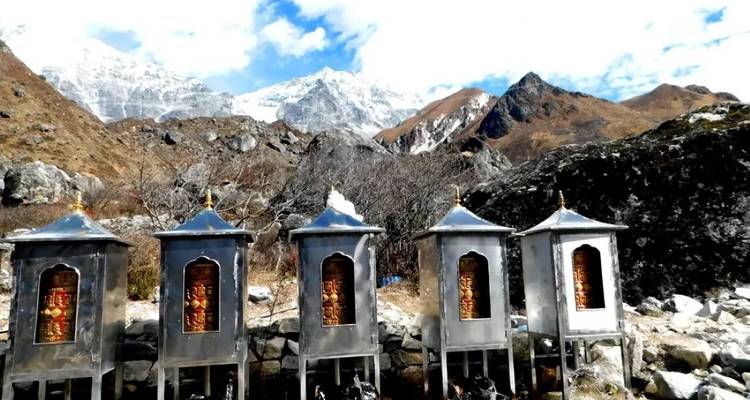 Moulins à prières en métal avec une chaîne de montagnes en arrière-plan.
