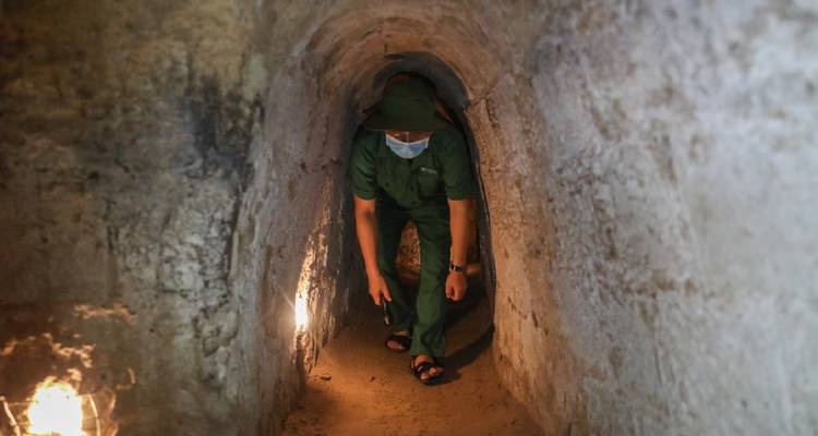 Un hombre con vestimenta militar explorando un túnel estrecho.