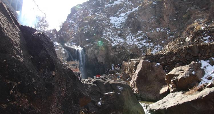 Kleine waterval in een rotsachtig landschap met toeristen.