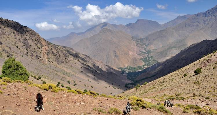 Uitgestrekte bergvallei met uitzicht op verre weg en dorp.