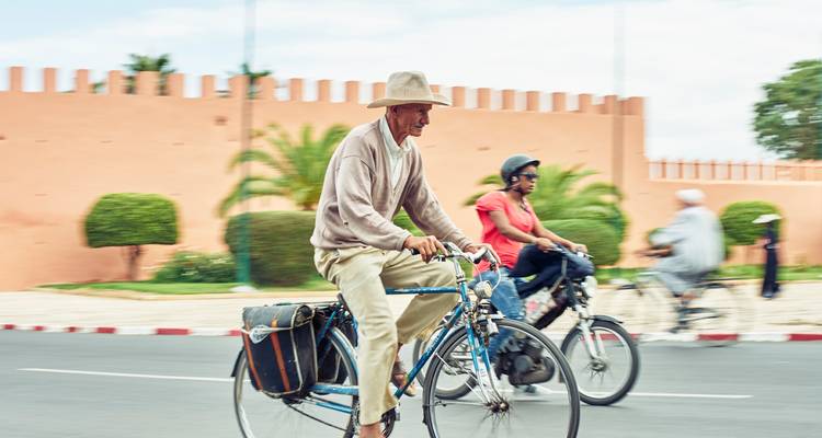 Des gens qui passent à vélo devant un mur de la ville.