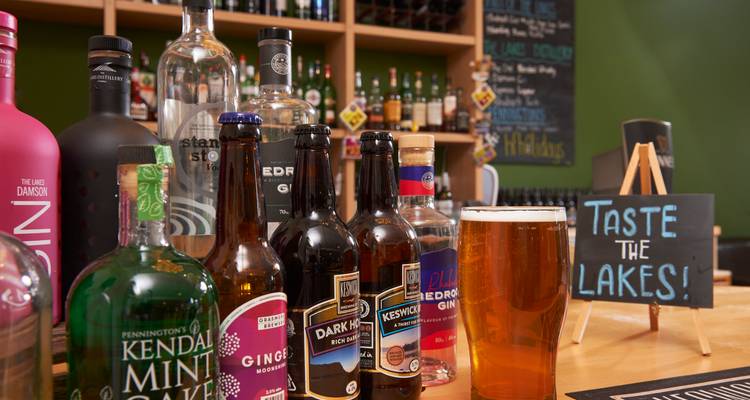 Variety of bottles and a pint of beer on a bar counter.