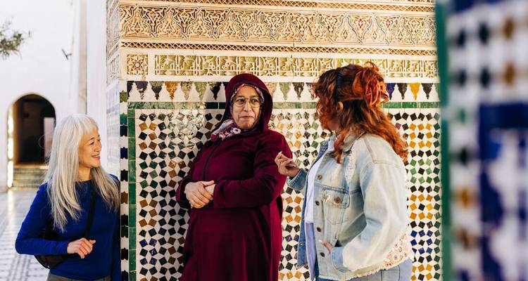 Drie vrouwen die converseren in een betegelde binnenplaats.