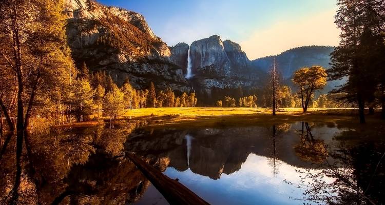 Weerspiegeling van Yosemite bergen en waterval in een serene meer.