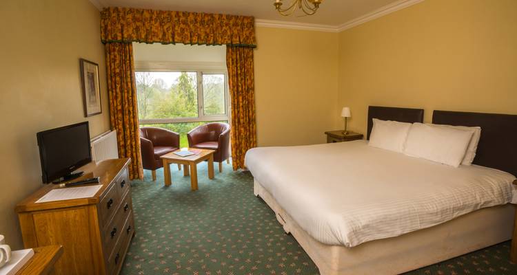 Ein Hotelzimmer mit einem Doppelbett, Fernseher und Fensterblick.