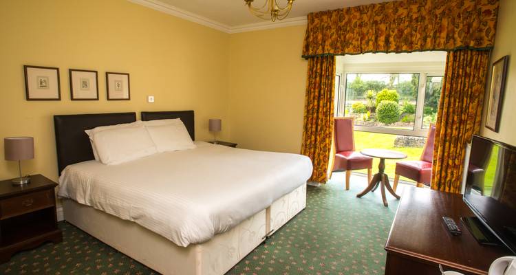 Ein Hotelzimmer mit einem Doppelbett und einer Sitzecke am Fenster.