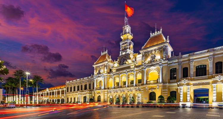 El Ayuntamiento de la Ciudad de Ho Chi Minh iluminado al anochecer con un cielo vibrante.