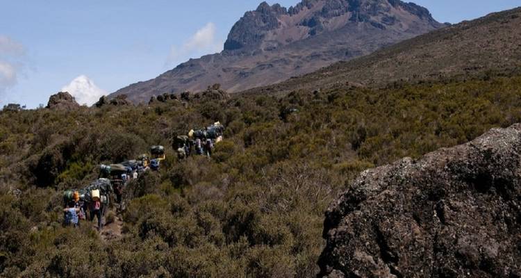 Wandergruppe auf einem Pfad vor einer bergigen Kulisse.