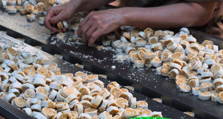 Des rangées de petites pâtisseries rondes en cours de préparation sur une table.