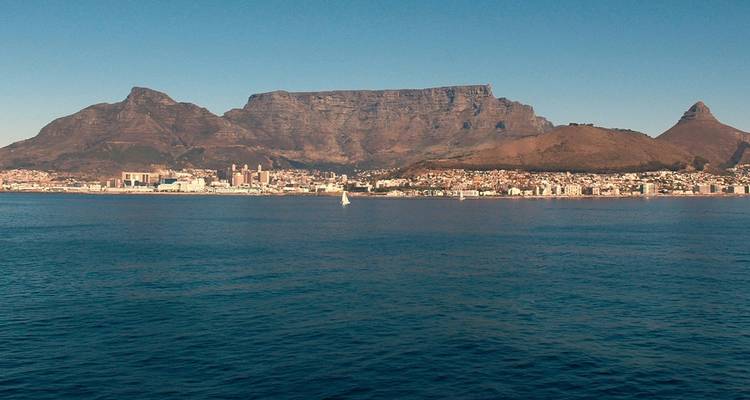 Stadtskyline mit ikonischer Bergkette im Hintergrund am Meer.