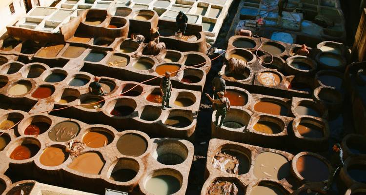 Tannerie traditionnelle marocaine avec des ouvriers teignant le cuir.