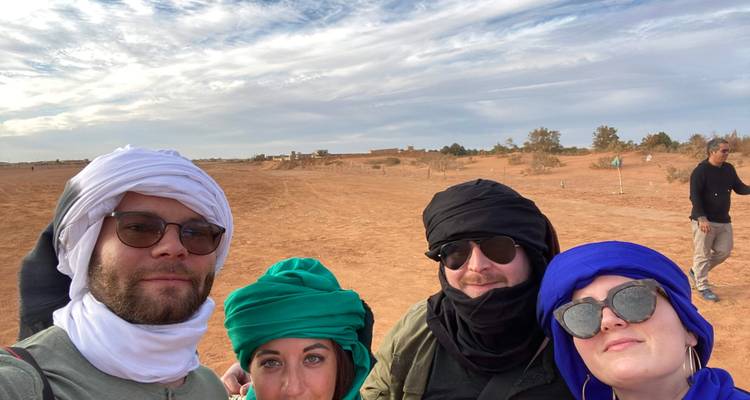 Groupe de personnes en tenue traditionnelle posant dans un paysage désertique.