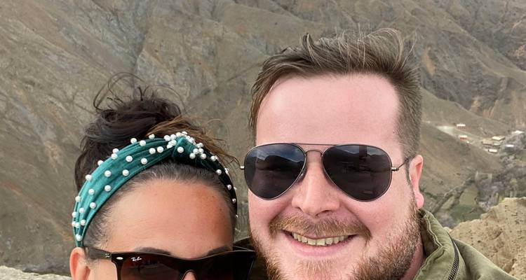 Deux personnes posant pour une photo avec un paysage montagneux en arrière-plan.