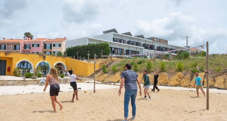Gruppe von Personen, die Volleyball auf einem sandigen Platz spielen.