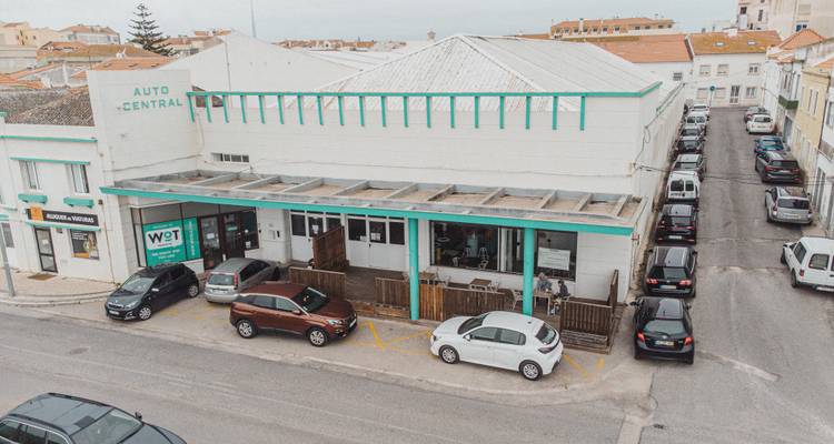 Straßenansicht mit geparkten Autos und einem zentralen Gebäude.