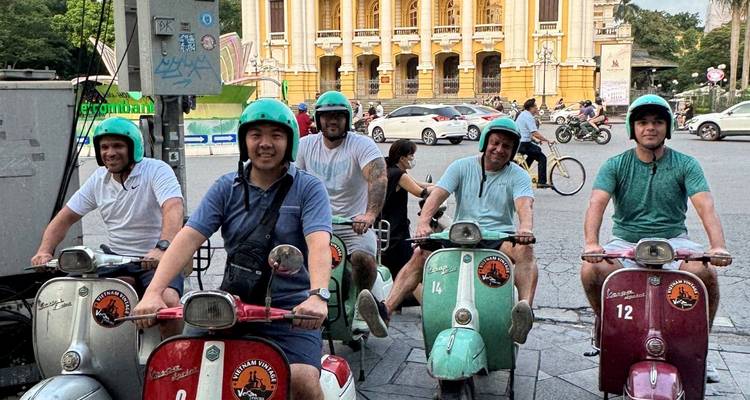 Eine Gruppe von Leuten auf Rollern, die vor einem historischen Gebäude posieren.