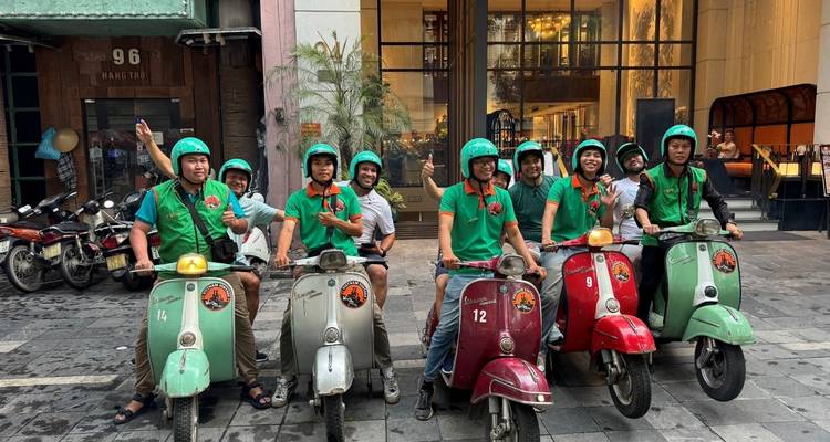 Eine Gruppe von Freunden, die auf Rollern vor einem modernen Gebäude posiert.