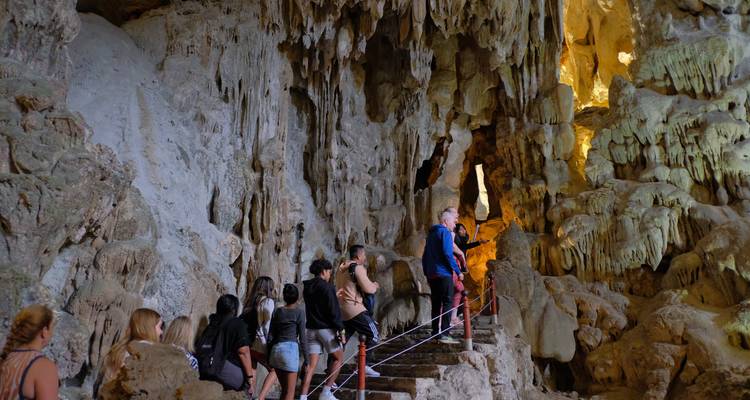 Toeristen die door een grot lopen met stalactieten en stalagmieten.