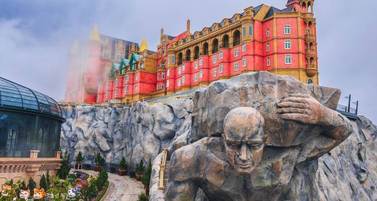 Kleurrijk pretpark met kasteelachtige gebouwen op een heuvel.