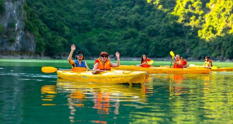 Grupo de personas navegando en kayak por un río turquesa con colinas verdes.