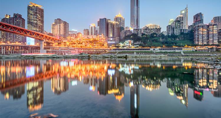 El skyline iluminado de Chongqing reflejado en el río al atardecer.