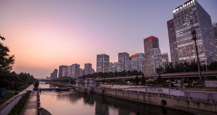 Les gratte-ciel modernes en verre de Pékin reflètent la lumière du crépuscule le long d'un paisible canal urbain.