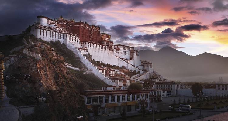 Potala-paleis verlicht door rijke zonsondergangskleuren met dramatische wolken boven Lhasa.