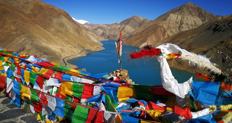 Landschapsfoto met een turquoise meer en gebedsvlaggen op de voorgrond.