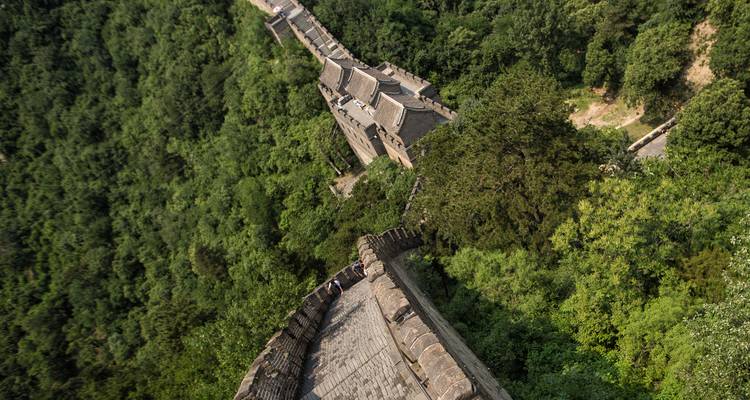 Vue aérienne de haut en bas d'une ancienne tour de guet de la Grande Muraille entourée d'une végétation dense.