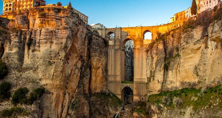 Un puente de piedra dramático que atraviesa una garganta profunda a la hora dorada en Ronda.
