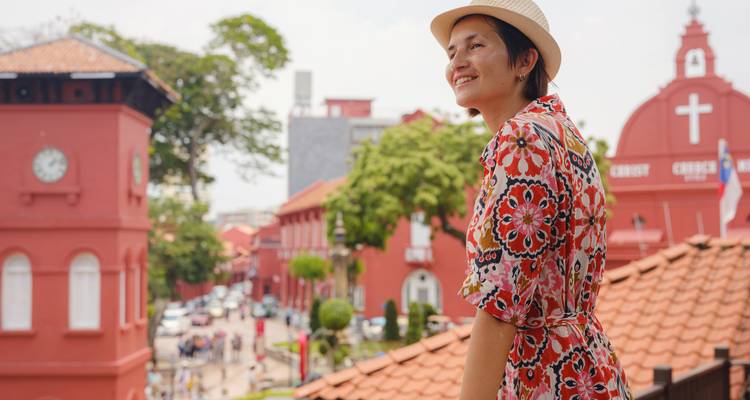 Smiling woman with red colonial buildings in the background.