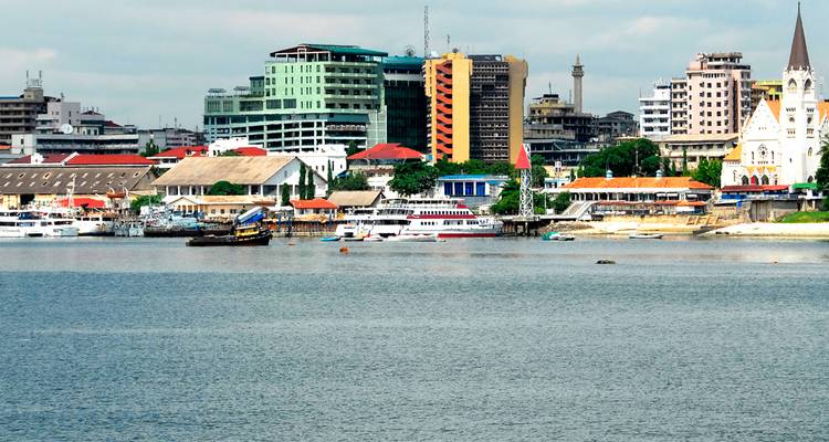 Skyline côtier de Dar es-Salaam présentant des traversiers, des bâtiments colorés et des eaux portuaires.