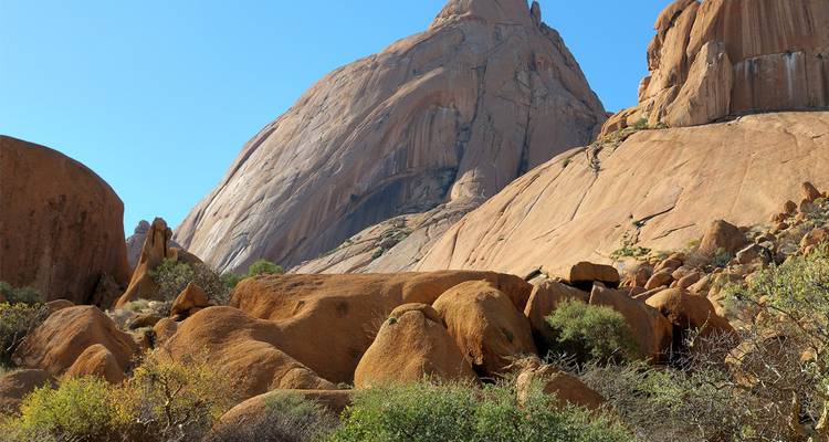 Rostfarbene Granitkuppeln und Felsblöcke des Spitzkoppe erheben sich steil in den klaren blauen Himmel