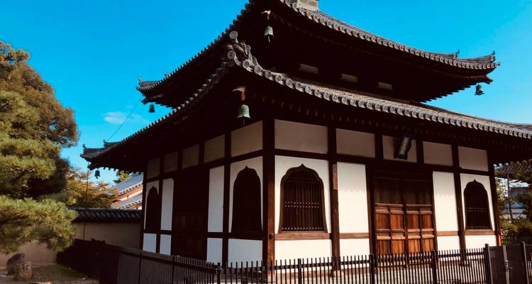 Pequeño edificio de templo de madera con techo de tejas que se encuentra bajo un cielo azul brillante.