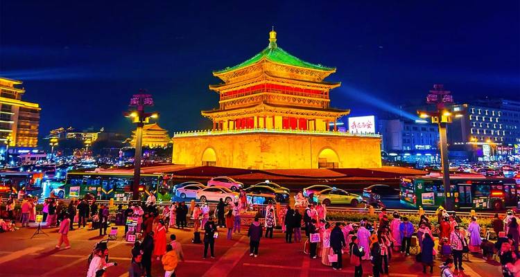 La Tour de la Cloche brillamment illuminée de Xi'an domine une scène nocturne animée remplie de circulation automobile et de clients.