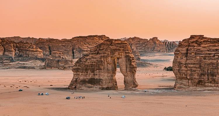Rote Felsbogenformation in einer Wüste bei Sonnenuntergang.