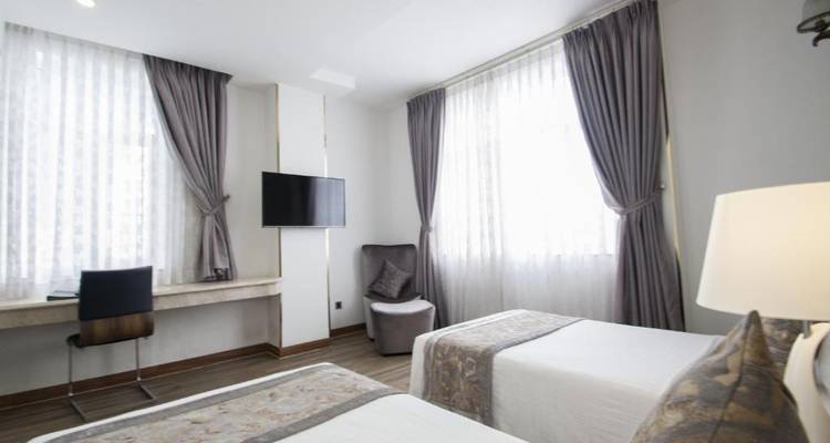 Hotelzimmerinnenraum mit zwei Einzelbetten, einem Fernseher und moderner Einrichtung.