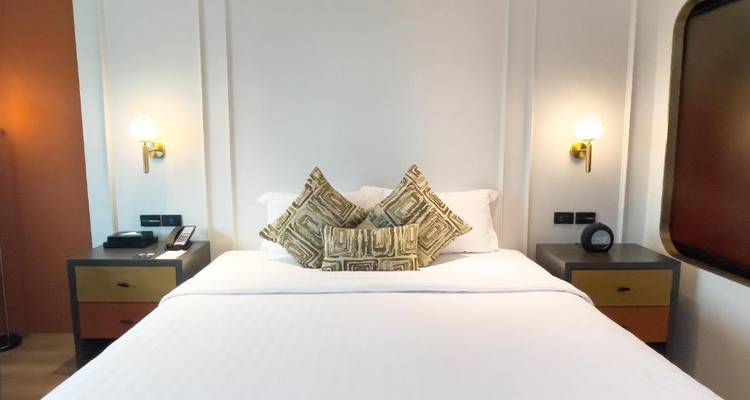 Gemütliches Hotelzimmer mit einem Einzelbett, Kissen und einem minimalistischen Design.