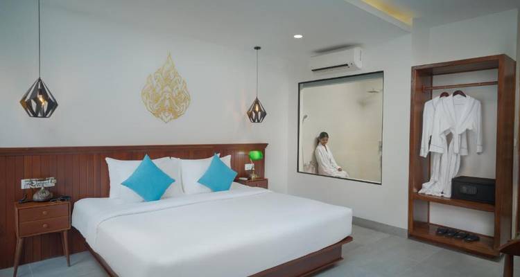 Hotelzimmer mit einem großen Bett, blauen Kissen und eleganter Einrichtung.