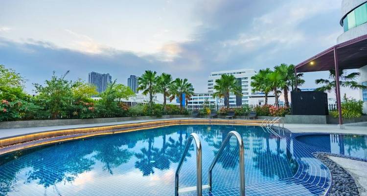 Außenschwimmbad mit Stadtblick, umgeben von Grün.