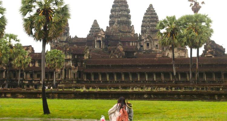 People sitting on a lawn with the Angkor Wat temple ahead.