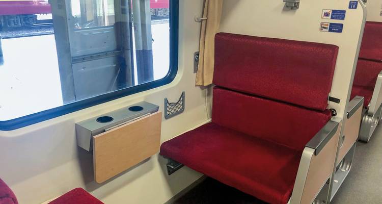 Intérieur d'un compartiment de train avec des sièges rouges.